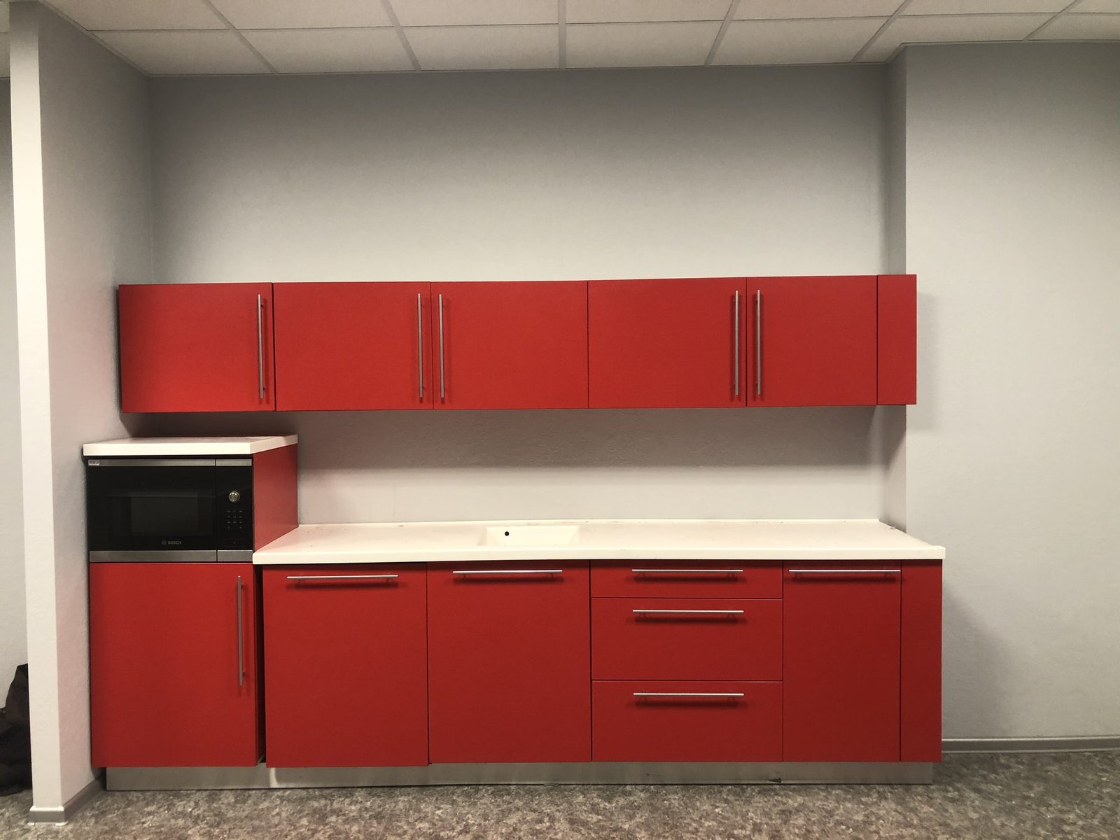 Cocina de oficina con muebles rojos.